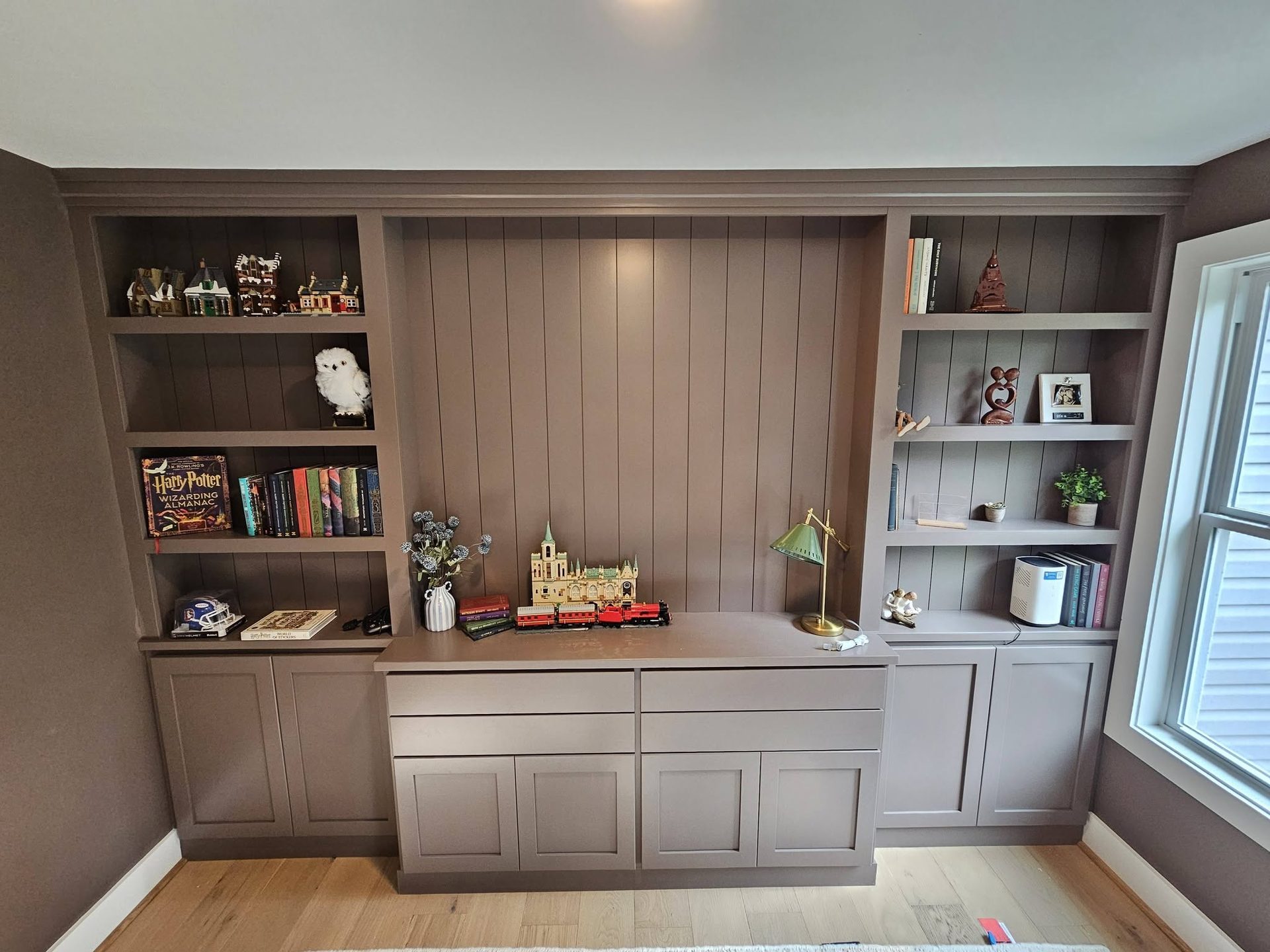 Built-in home office and library with gray shaker cabinetry, a desk run, and upper open shelves styled with books
