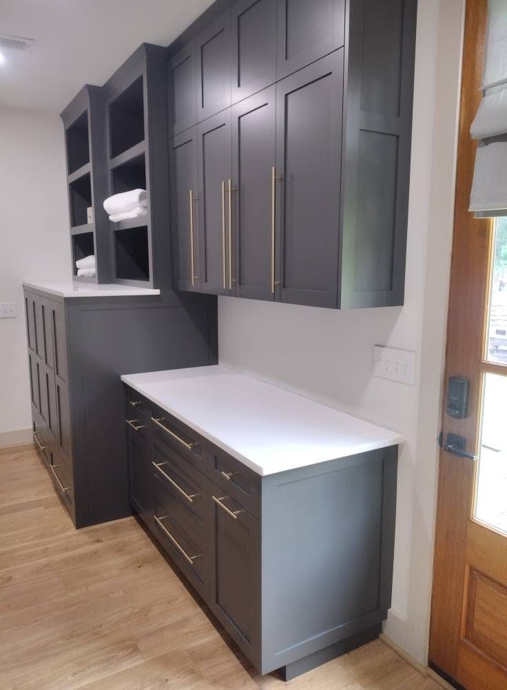 Gray upper cabinets over a base cabinet with a white counter and a glass-panel door alongside