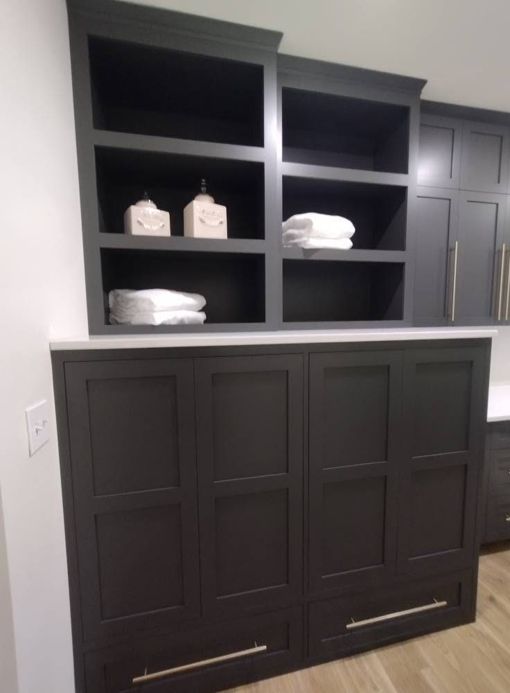 Built-in with open display shelves over shaker lower cabinets and a white counter, used as a linen and utility built-in